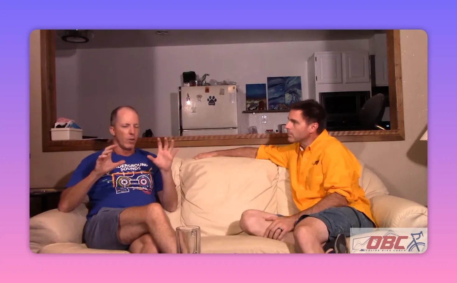 Two men on a couch discussing W′ and critical power, one using hand gestures to illustrate recovery mismatch