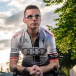 Professional profile shot of Richard Wharton, a veteran cycling coach, smiling and looking confidently slightly off-camera.